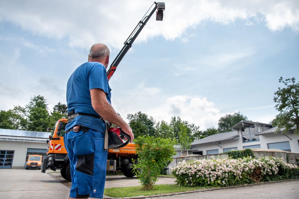 Mitarbeiter des Betriebshof bedient den Kranarm des Kippers mit der Fernbedingung