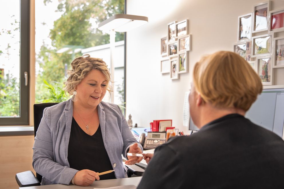 Mitarbeiterin des Standesamtes spricht mit einer Bürgerin am Schreibtisch